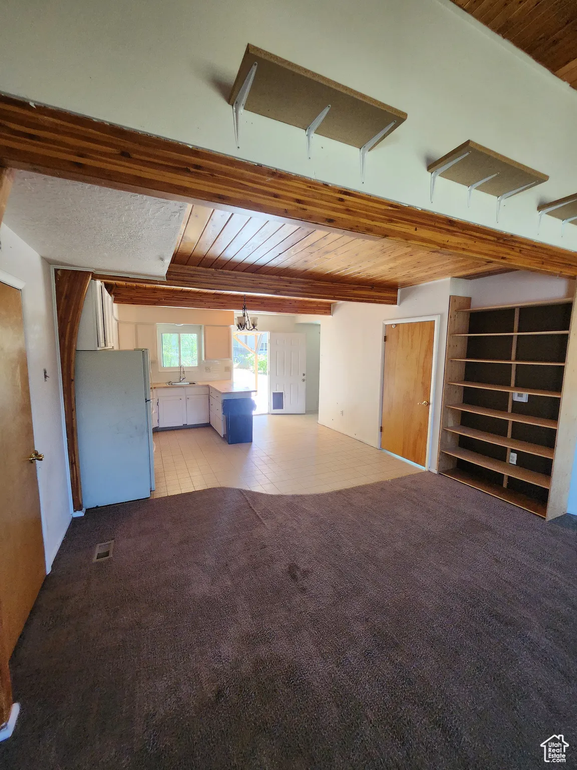 Unfurnished living room featuring wood ceiling, carpet, and a chandelier