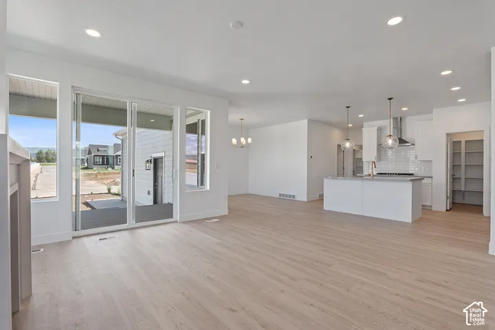 Unfurnished living room with light wood-type flooring, a chandelier, and recessed lighting