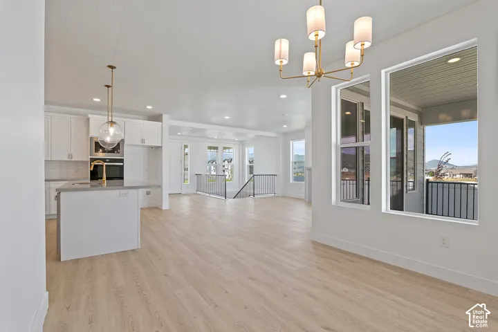 Kitchen featuring open floor plan, white cabinetry, light wood-style flooring, recessed lighting, and appliances with stainless steel finishes