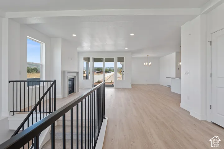 Hallway with light wood-style floors, a chandelier, recessed lighting, and an upstairs landing