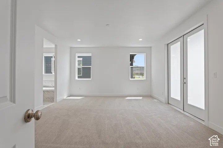Carpeted spare room featuring french doors and recessed lighting