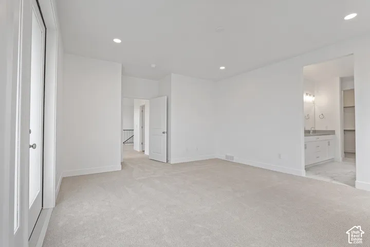 Unfurnished bedroom with light colored carpet, recessed lighting, and ensuite bath