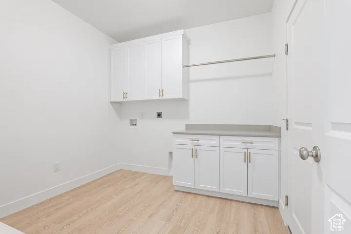 Laundry room featuring hookup for an electric dryer, cabinet space, light wood-style floors, and hookup for a washing machine