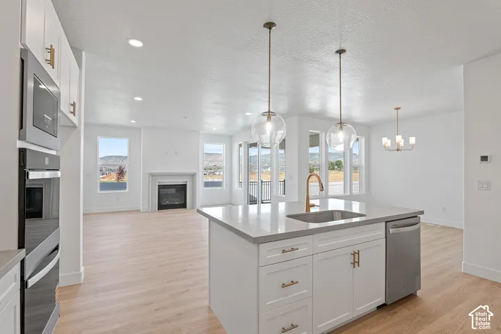Kitchen with a glass covered fireplace, plenty of natural light, light wood-style flooring, a textured ceiling, and recessed lighting