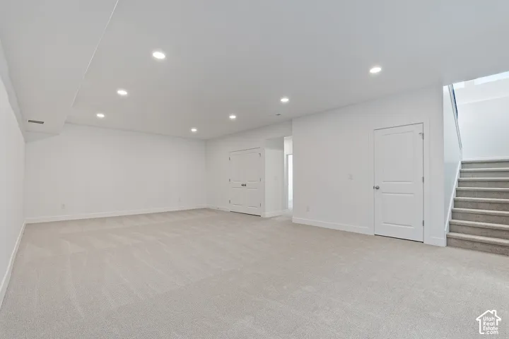 Below grade area featuring light carpet, stairway, and recessed lighting