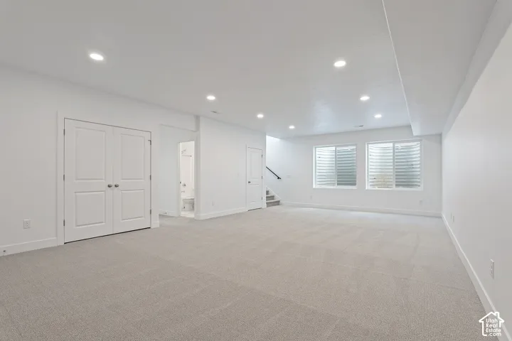 Below grade area featuring light carpet, recessed lighting, and stairs