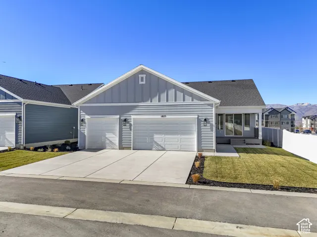 Ranch-style house with board and batten siding, concrete driveway, an attached garage, and roof with shingles