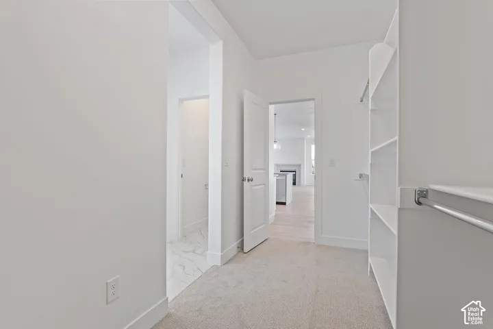 Corridor featuring baseboards and light colored carpet