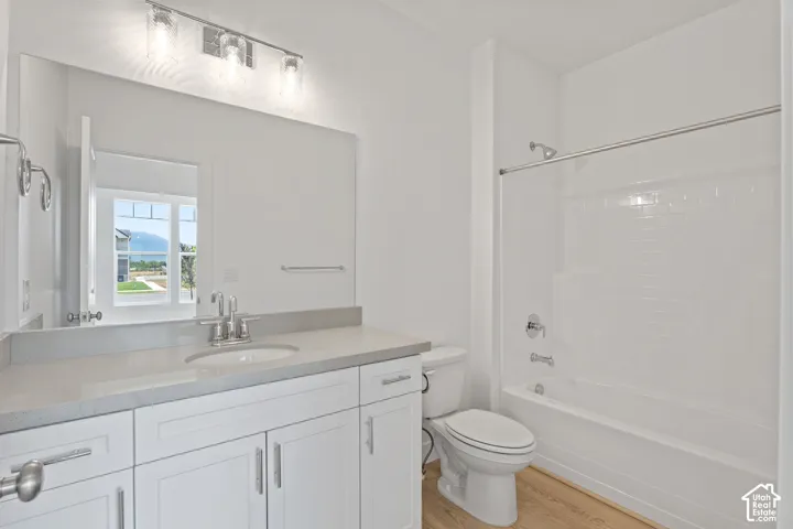 Bathroom with vanity, wood finished floors, and bathtub / shower combination