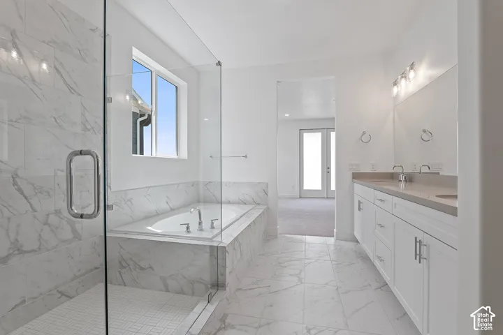 Full bath with marble look tile flooring, a bath, double vanity, a marble finish shower, and french doors