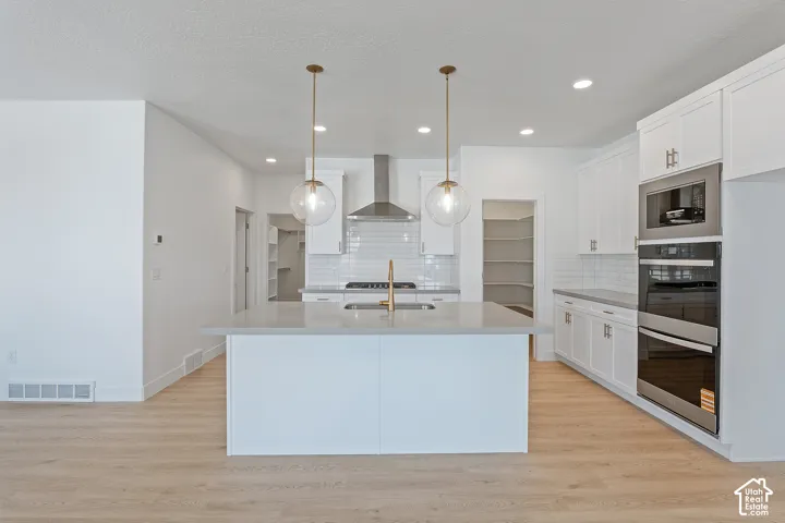 Kitchen featuring backsplash, stainless steel double oven, light countertops, white cabinets, and recessed lighting