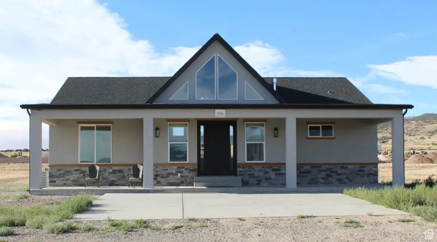 View of front of house with stone siding, stucco siding, and covered porch