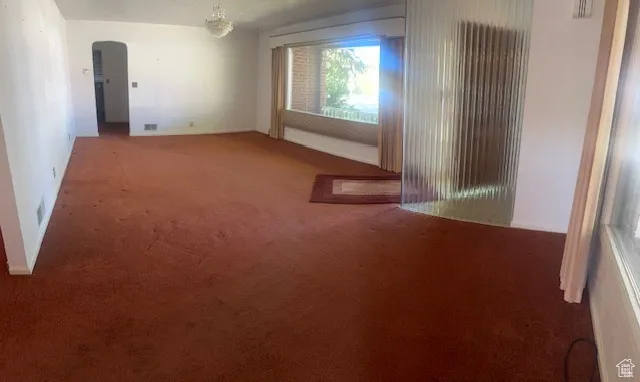 Carpeted spare room with arched walkways and baseboards