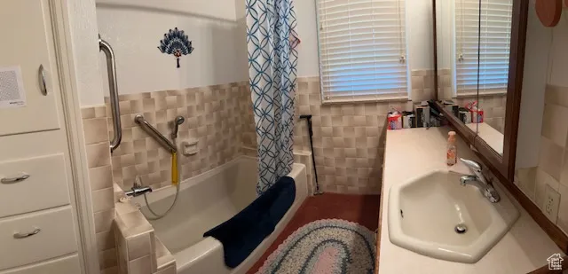 Full bathroom with tile walls, shower / bath combo, and wainscoting