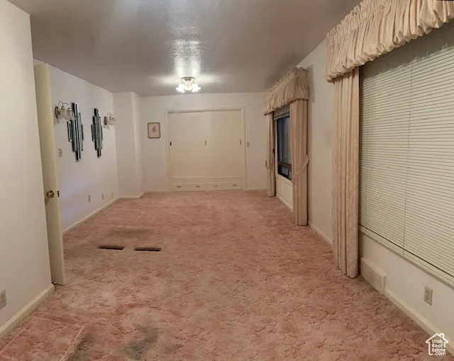 Hall featuring light colored carpet and a textured ceiling