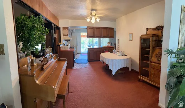 Dining area with a ceiling fan, light colored carpet, and a textured ceiling