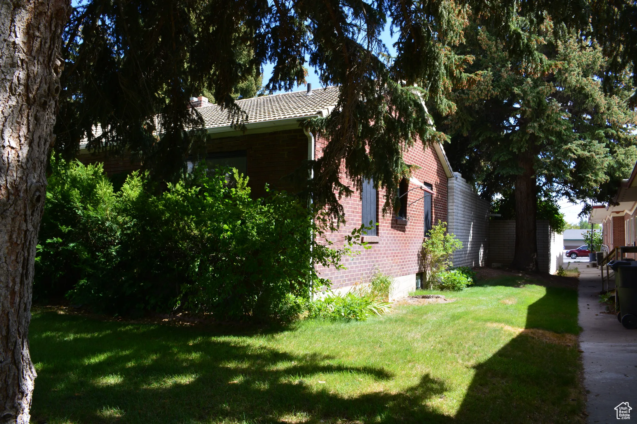 View of side of home with a lawn, a tiled roof, and brick siding