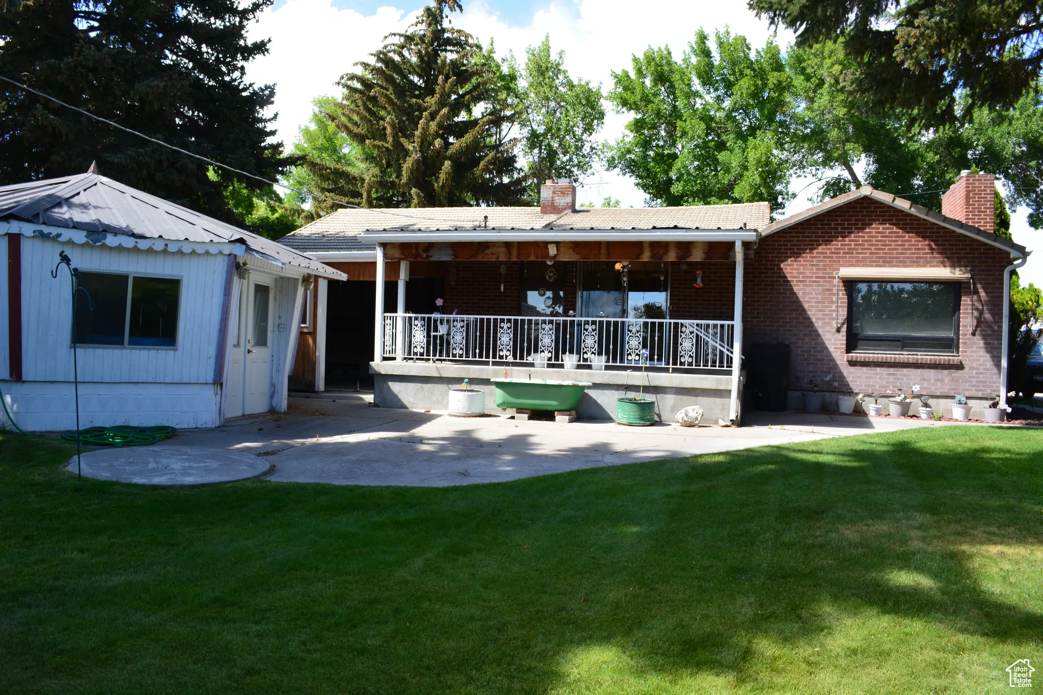 Rear view of property with a chimney, a lawn, and a porch