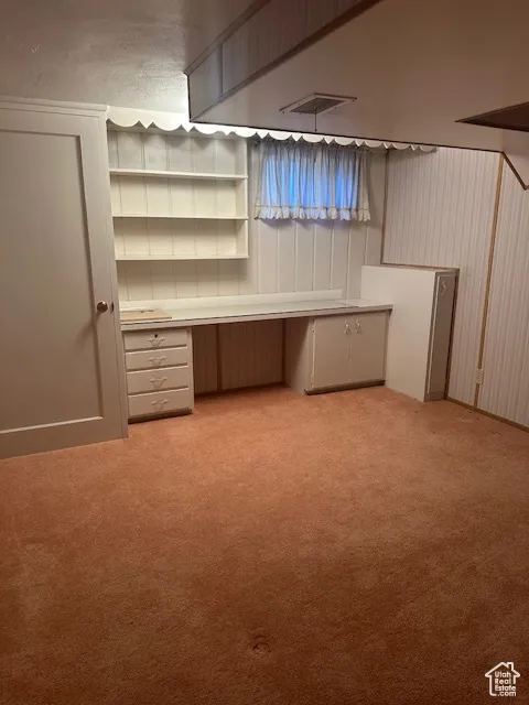 Finished below grade area featuring light colored carpet and a desk