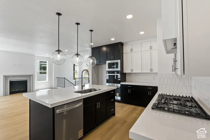 Kitchen with dark cabinets, backsplash, appliances with stainless steel finishes, light countertops, and recessed lighting