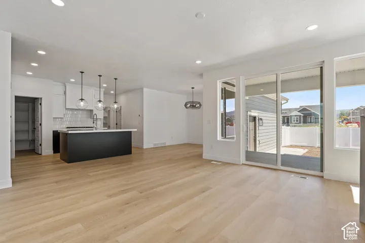 Unfurnished living room featuring light wood-style flooring, recessed lighting, and a chandelier