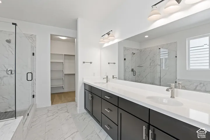 Full bathroom featuring marble finish flooring, a marble finish shower, double vanity, a walk in closet, and recessed lighting