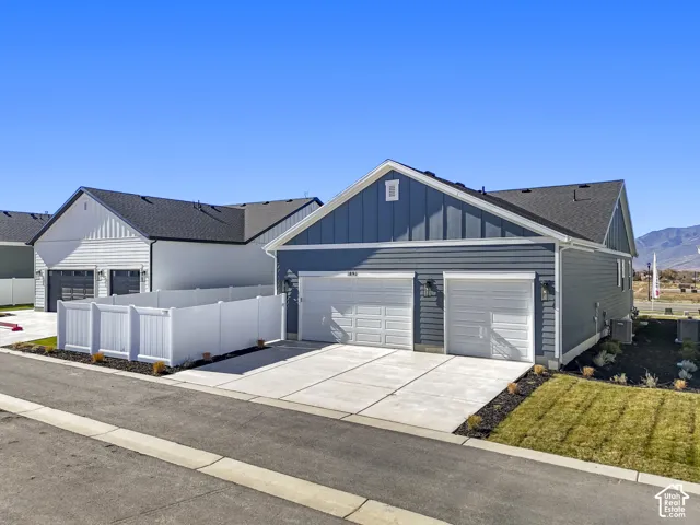 View of front of house with board and batten siding, concrete driveway, a shingled roof, and an attached garage