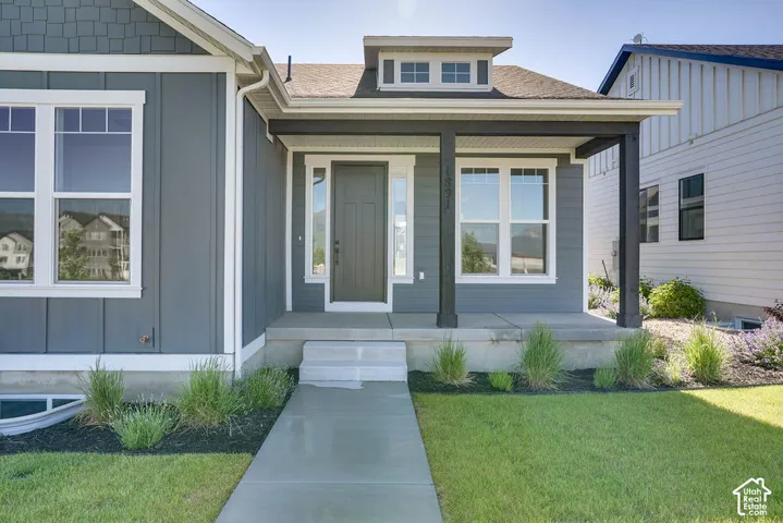 Modern gray siding exterior with white trim and a covered front porch featuring dark structural columns