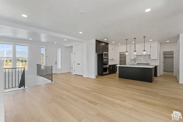 Kitchen featuring light countertops, light wood-style floors, open floor plan, tasteful backsplash, and recessed lighting