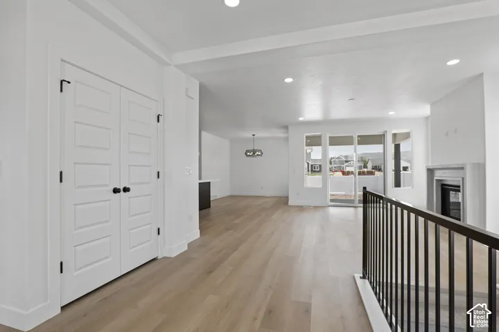 Corridor featuring light wood finished floors, recessed lighting, and a chandelier
