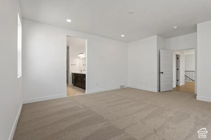 Unfurnished bedroom featuring light colored carpet, recessed lighting, and ensuite bathroom