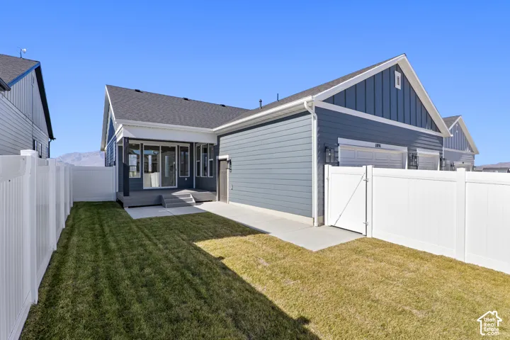 Back of house featuring a fenced backyard, a gate, board and batten siding, a patio, and roof with shingles