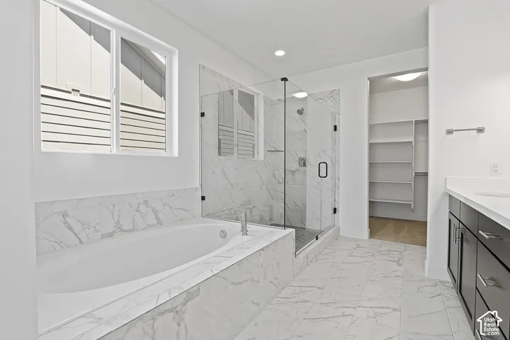 Bathroom with a garden tub, a marble finish shower, marble look tile flooring, vanity, and recessed lighting
