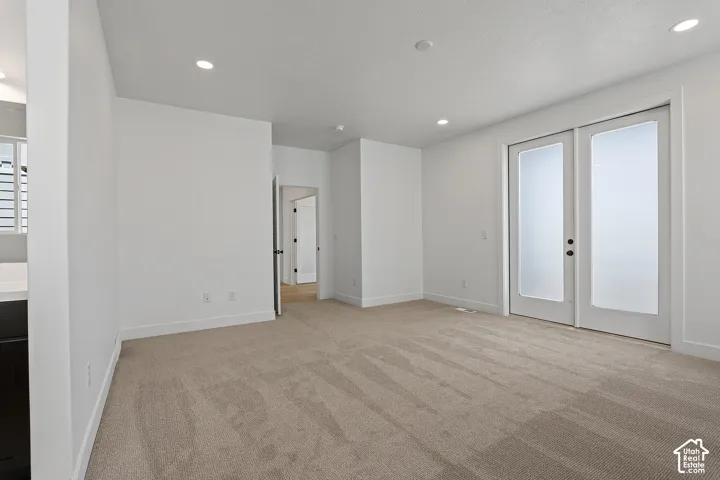Unfurnished room featuring french doors, light colored carpet, and recessed lighting
