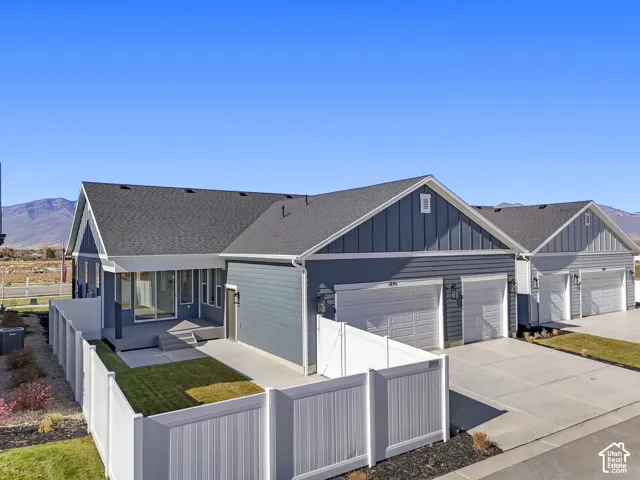View of front of house featuring a fenced front yard, board and batten siding, driveway, roof with shingles, and a mountain view