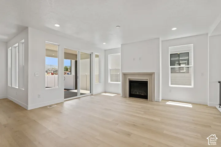 Unfurnished living room featuring light wood-style floors, a fireplace, a textured ceiling, and recessed lighting