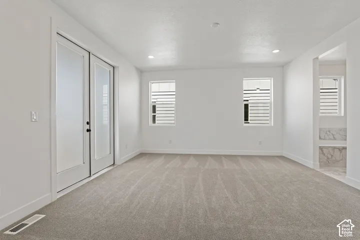 Spare room with light colored carpet, a textured ceiling, and recessed lighting