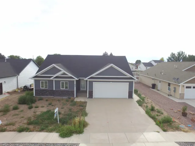 Modern ranch-style home featuring gray siding, dark stone accents, white trim, and a dark shingled roof