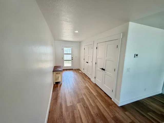 Entryway featuring wood-finish flooring, white walls, and a modern glass-panel front door