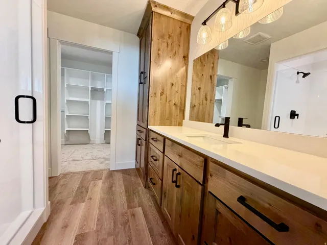 Bathroom vanity featuring wood-finish cabinetry, white countertop, rectangular undermount sink, and matte black fixtures