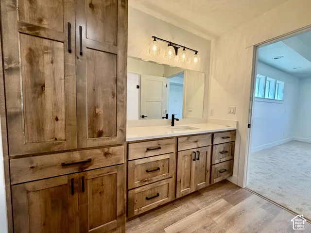 Bathroom vanity featuring wood-finish cabinetry, a white countertop, and a single basin sink with a black faucet