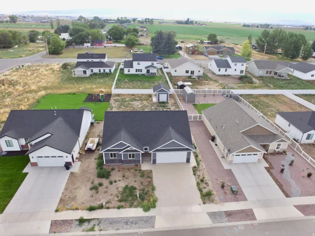 Ranch-style residence featuring a gray exterior with stone accents, a two-car garage, and a dark shingle roof