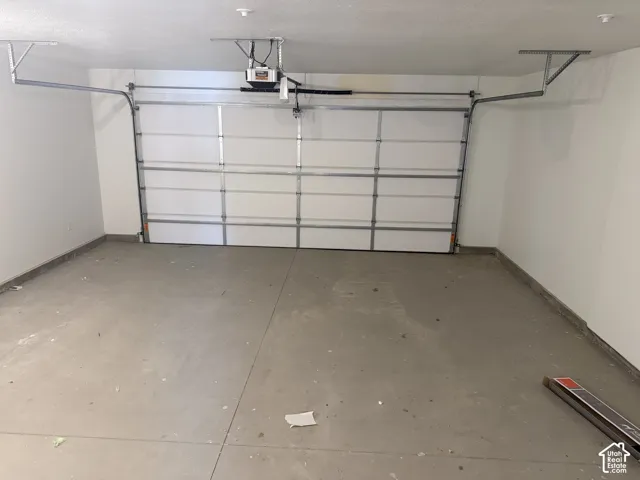 Spacious garage featuring a concrete floor, white walls, and an overhead garage door with an automatic opener