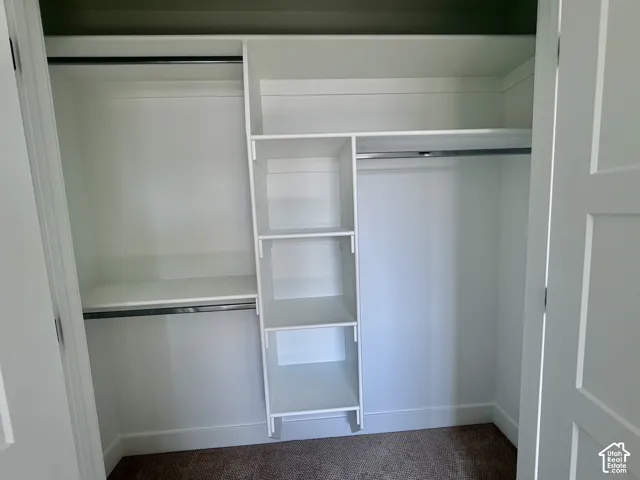 Built-in closet system featuring white shelving, multiple hanging rods, and an integrated shelf unit