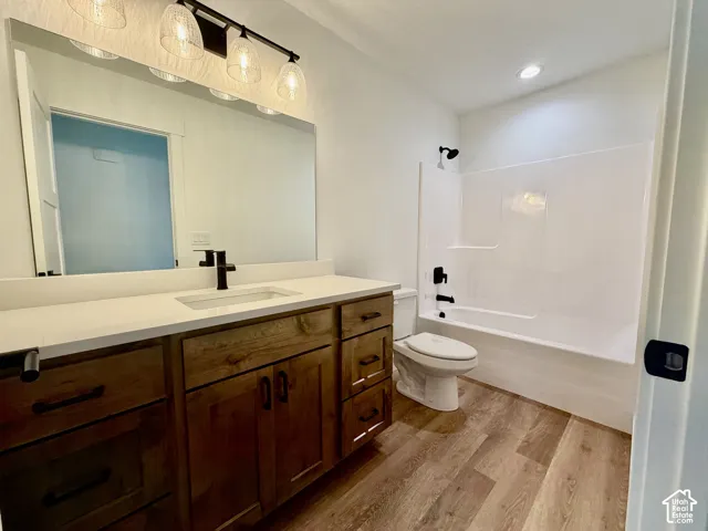 Bathroom featuring a wood-finish vanity with a light-toned countertop, an undermount sink, and a black faucet