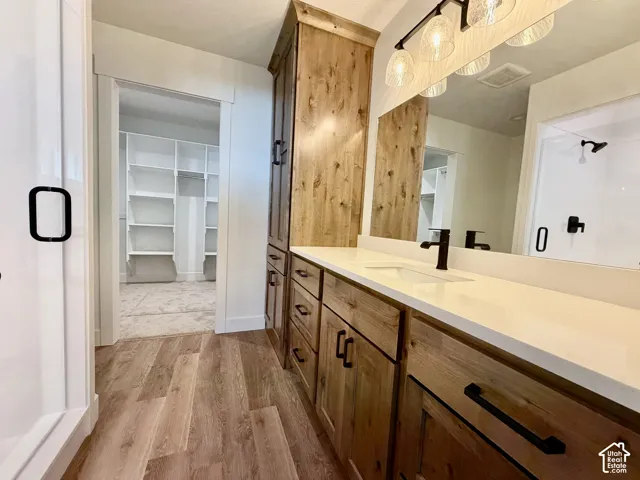 Bathroom vanity featuring wood-finish cabinetry, white countertop, rectangular undermount sink, and matte black fixtures
