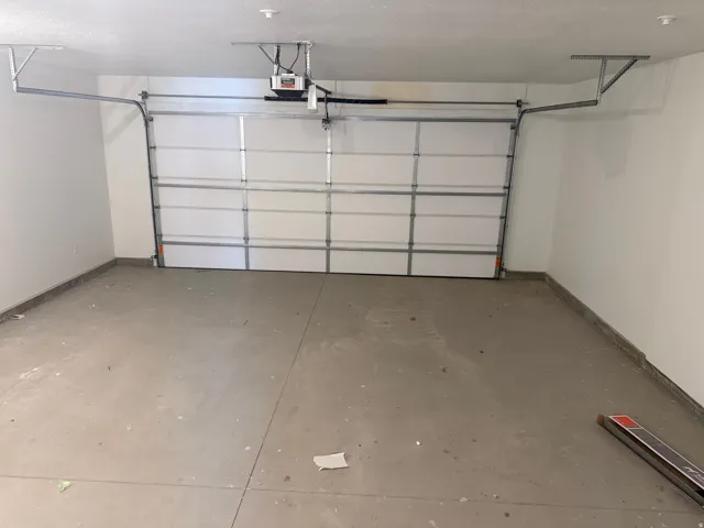 Spacious garage featuring a concrete floor, white walls, and an overhead garage door with an automatic opener