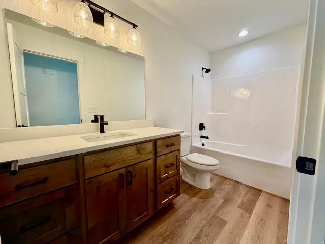 Bathroom featuring a wood-finish vanity with a light-toned countertop, an undermount sink, and a black faucet