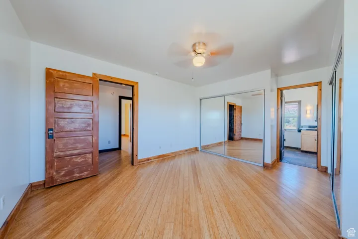 Unfurnished bedroom featuring wood finished floors, a closet, and ceiling fan