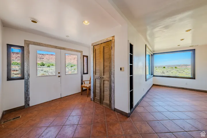 Foyer entrance with plenty of natural light, recessed lighting, french doors, and dark tile patterned floors